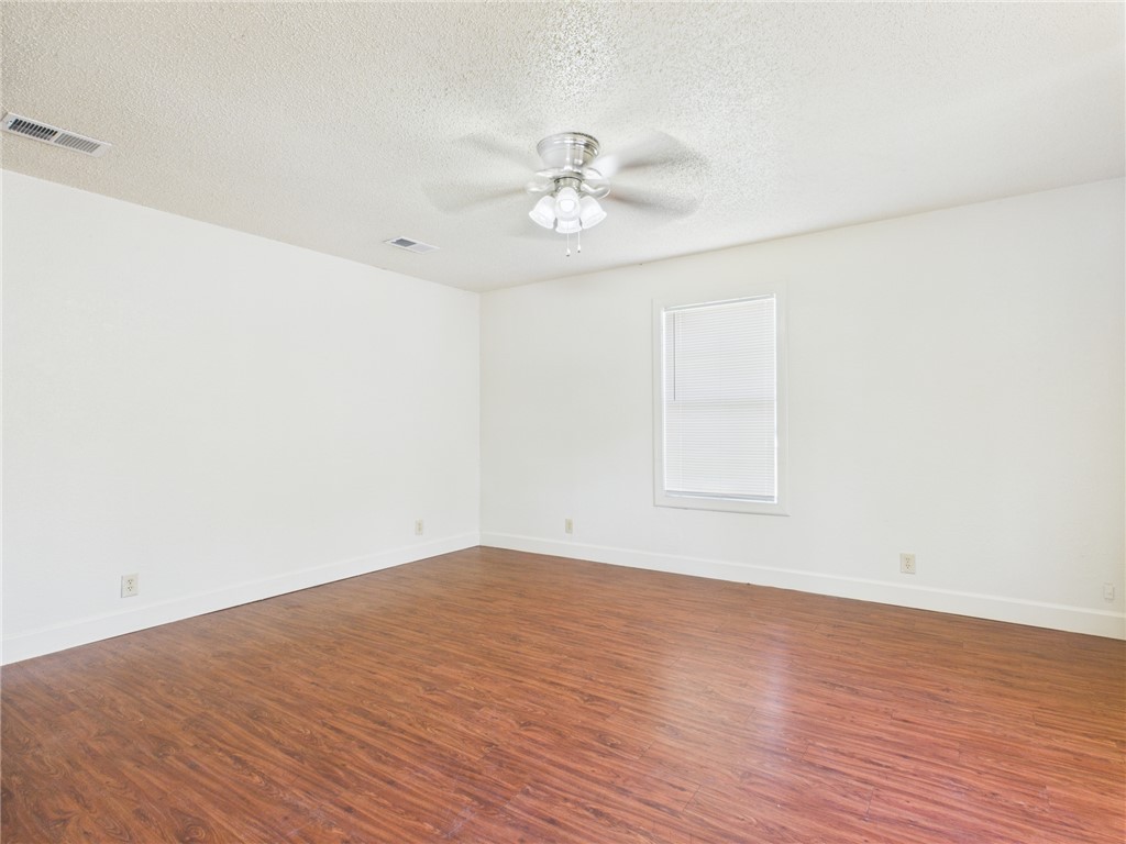 2702 Cavitt Avenue Bryan, TX 77801 - Photo 5 of 21 Empty room featuring a textured ceiling, dark wood-type flooring, and a ceiling fan