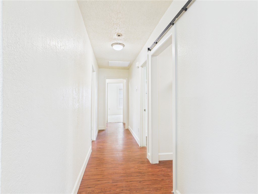 2702 Cavitt Avenue Bryan, TX 77801 - Photo 6 of 21 Hall with light wood-type flooring, a barn door, and a textured ceiling