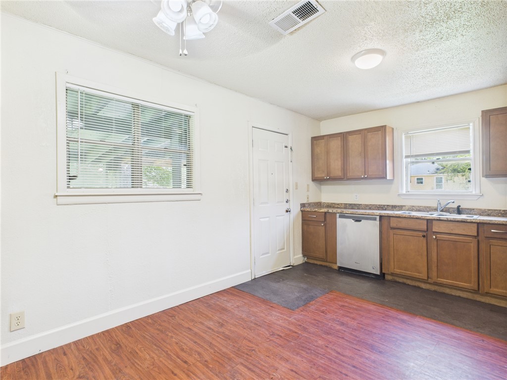 2702 Cavitt Avenue Bryan, TX 77801 - Photo 7 of 21 Kitchen featuring brown cabinetry, a textured ceiling, dark wood finished floors, dishwasher, and light countertops