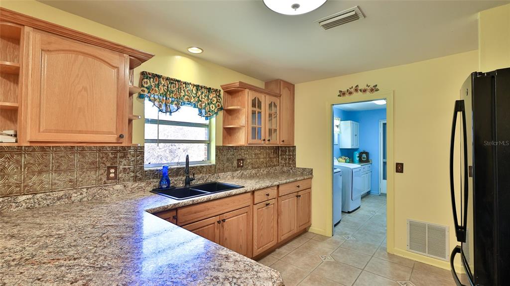 725 Green Road New Smyrna Beach, FL 32168 - Photo 23 of 40 a kitchen with a sink a refrigerator and cabinets