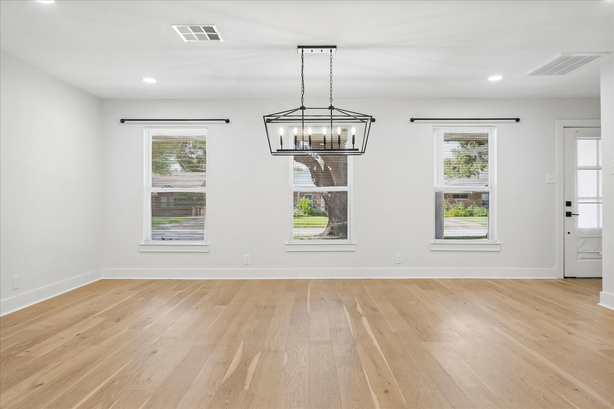 Dining room features exquisite engineered hardwood floors, abundant windows & stylish light fixture.