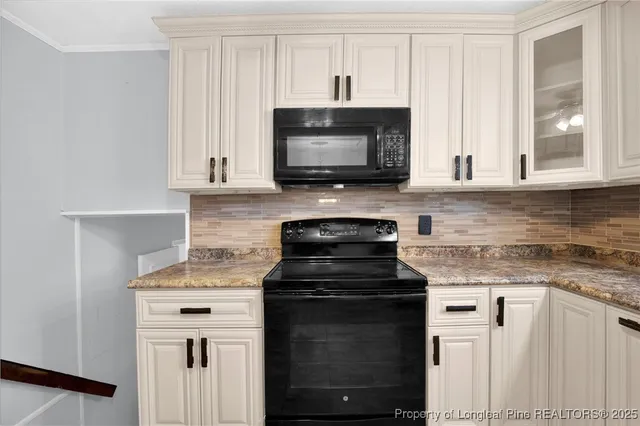 a kitchen with granite countertop white cabinets and black appliances