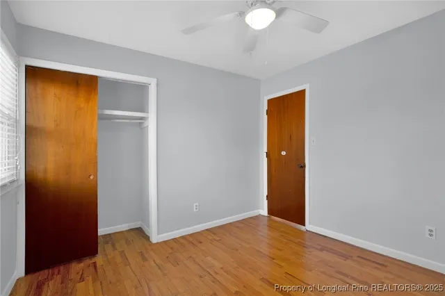 a view of an empty room with wooden floor and closet