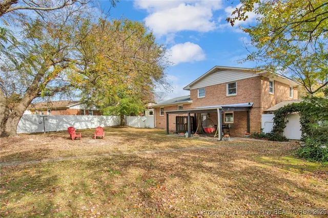a view of a house with large trees and sitting area
