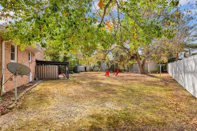 a backyard of a house with table and chairs and wooden fence