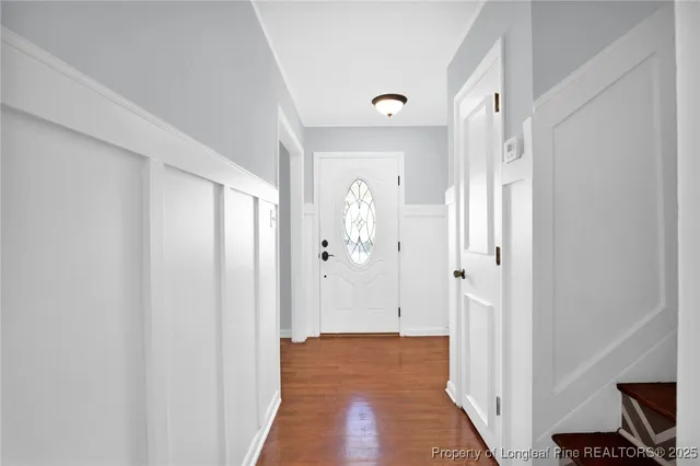 a view of a hallway with wooden floor and a bathroom