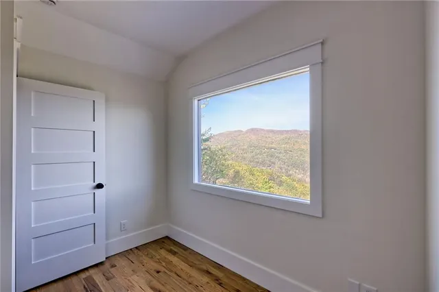 a view of a hallway with wooden floor and chandelier fan