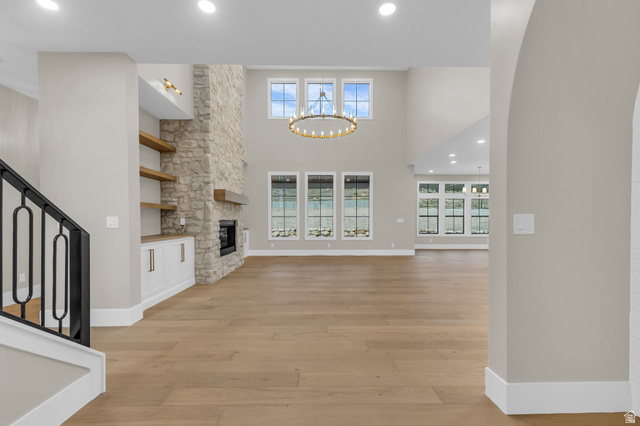 2828 Jojo Road Eagle Mountain, UT 84005 - Photo 5 of 63 Spacious open-concept living area featuring a stone-clad fireplace with a wooden mantel, custom built-in cabinetry, and floating shelves