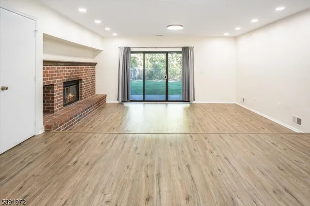 a view of an empty room with wooden floor and a fireplace
