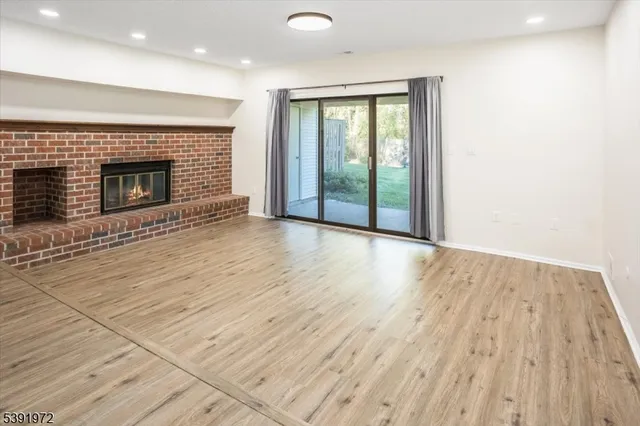 an empty room with wooden floor fireplace and windows