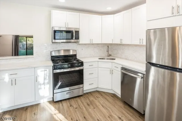 a kitchen with cabinets stainless steel appliances and wooden floor