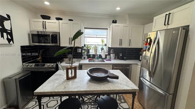 a kitchen with stainless steel appliances granite countertop a refrigerator a stove a sink dishwasher and white cabinets with wooden floor