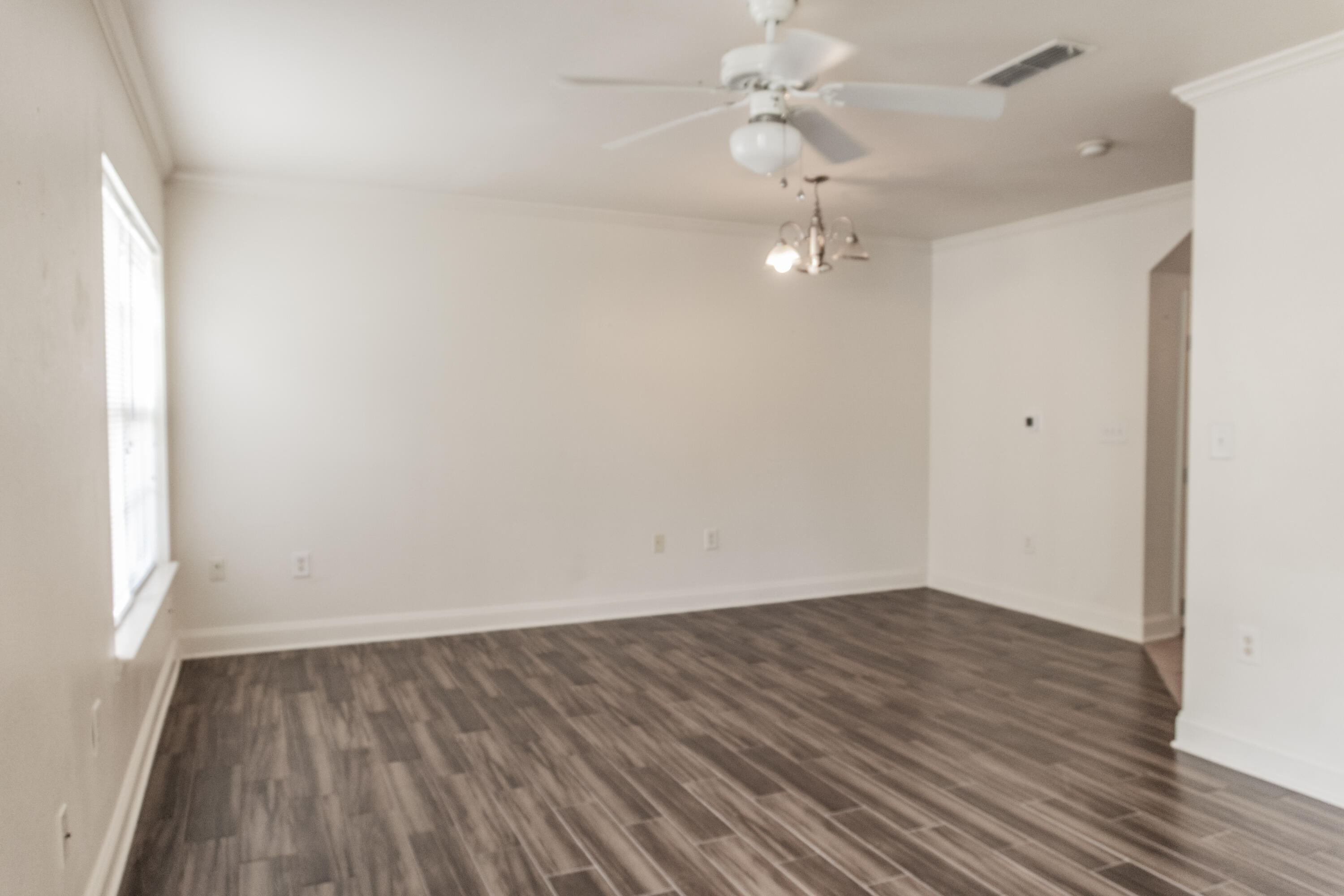 560 Wingspan Way Crestview, FL 32536 - Photo 6 of 18 an empty room with wooden floor fan and windows