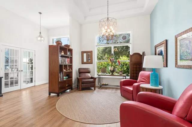 a living room with furniture a chandelier and wooden floor