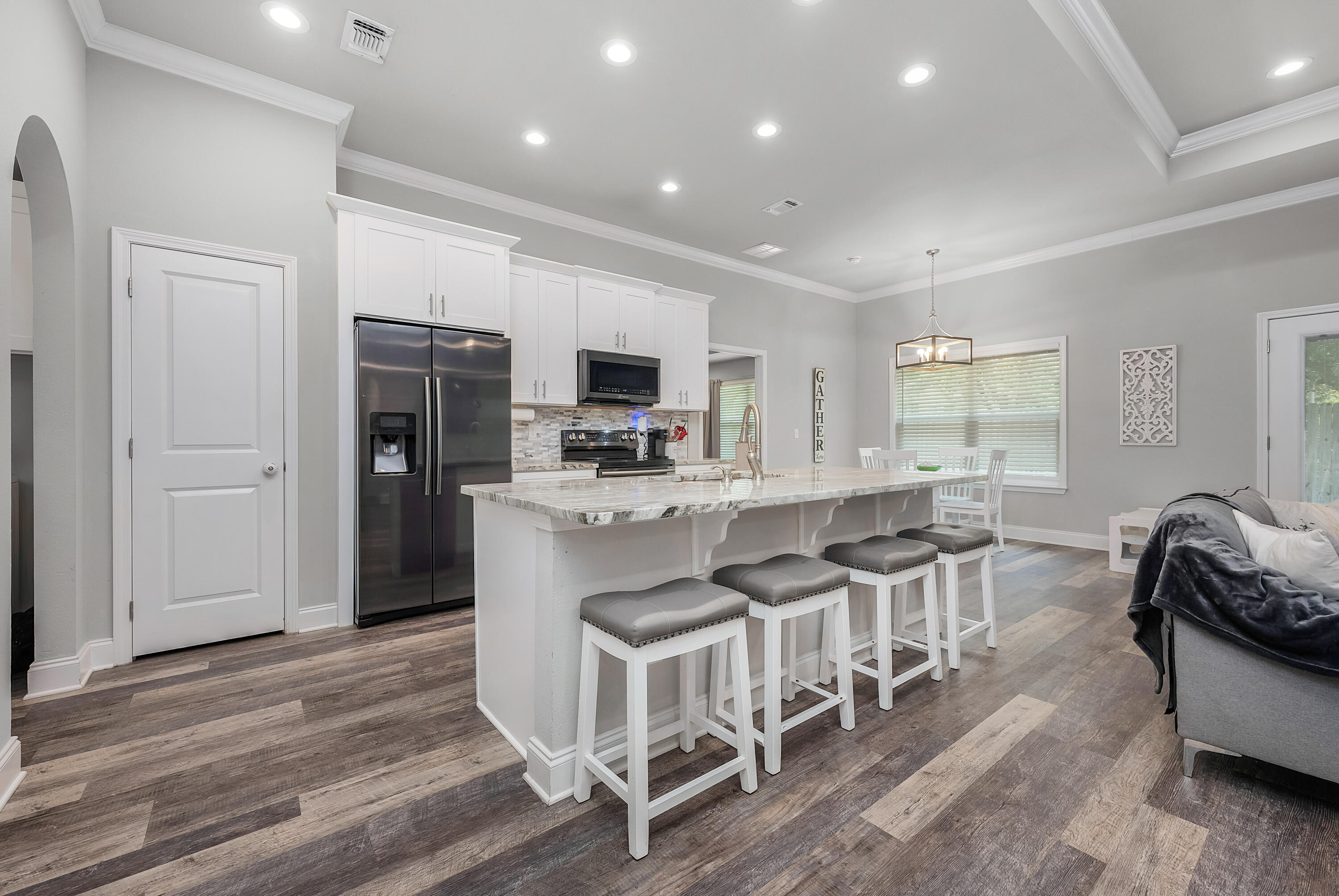 820 Hilltop Road Mary Esther, FL 32569 - Photo 21 of 47 a kitchen with stainless steel appliances kitchen island granite countertop a refrigerator a stove a sink a dining table and chairs with wooden floor