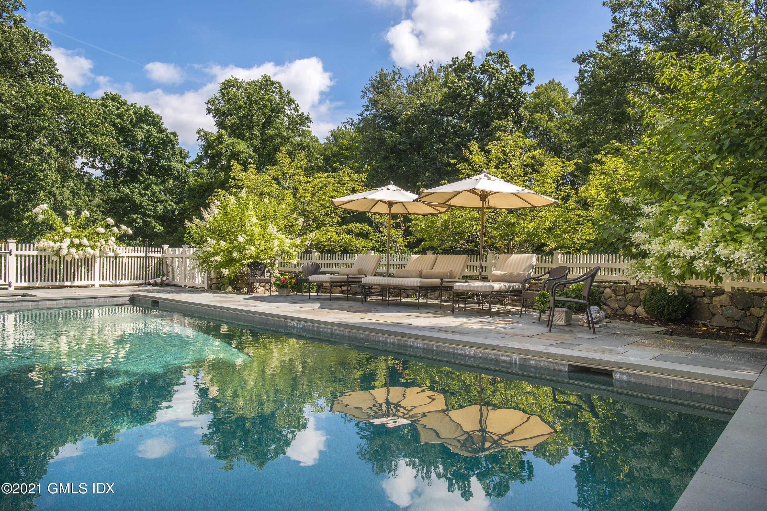 65 Clapboard Ridge Road Greenwich, CT 06830 - Photo 3 of 36 a view of a swimming pool with lawn chairs under an umbrella