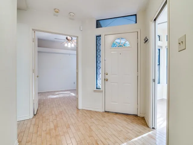 a view of an empty room and bathroom with wooden floor