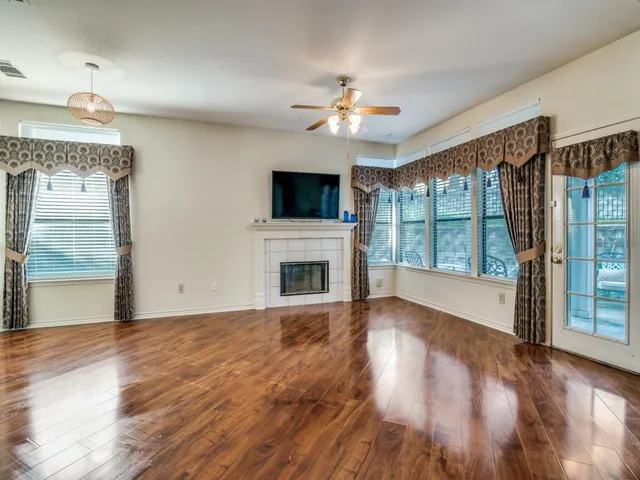 a view of an empty room with wooden floor and a fireplace
