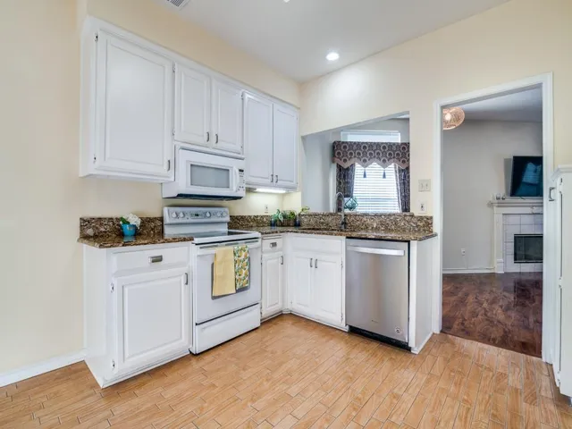a kitchen with granite countertop white cabinets and white appliances