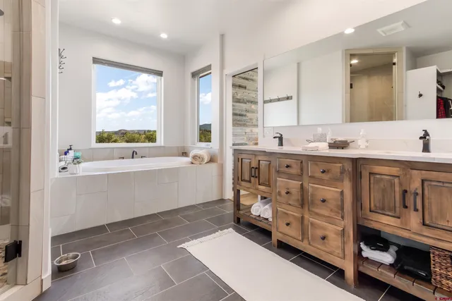 a bathroom with double vanity sink a mirror a window and vanity