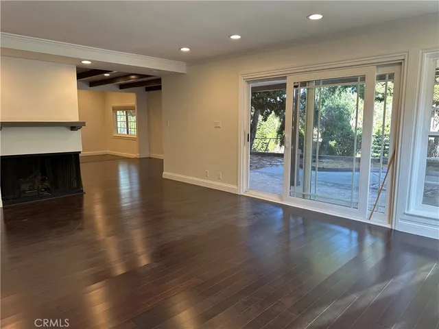 an empty room with wooden floor fireplace and windows