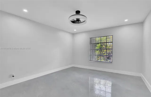 an empty room with a window and a ceiling fan