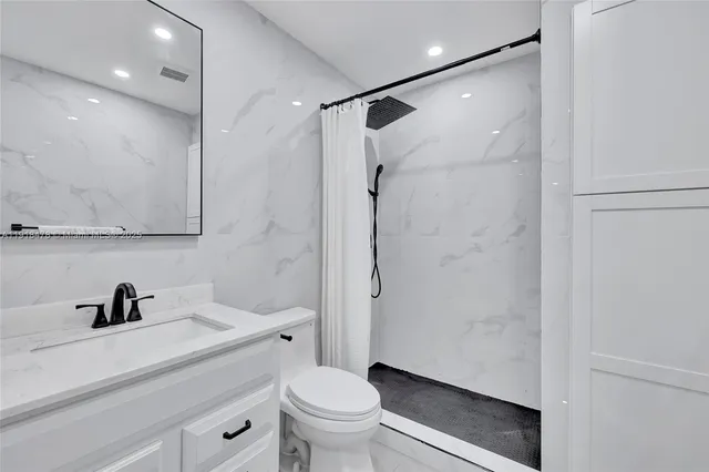 a bathroom with a shower sink vanity mirror and toilet