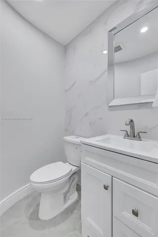 a bathroom with a granite countertop toilet sink mirror and vanity