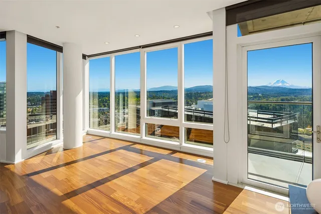 a view of a room with a large window and wooden floor