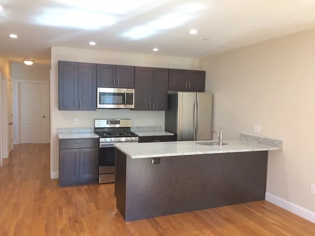 a kitchen with stainless steel appliances granite countertop a stove a sink a refrigerator and a microwave