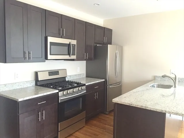 a kitchen with granite countertop cabinets stainless steel appliances and wooden floor