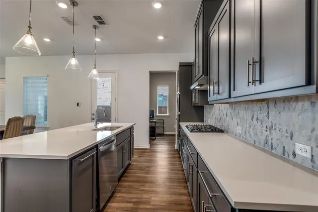 a kitchen with granite countertop a sink a counter top space stainless steel appliances and cabinets