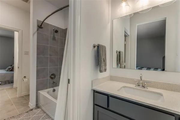 a bathroom with a granite countertop sink a mirror a bathtub and shower