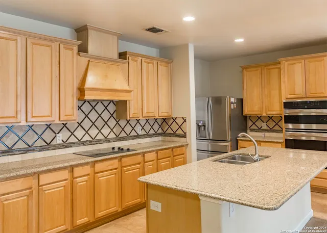 a kitchen with kitchen island granite countertop a sink and a refrigerator