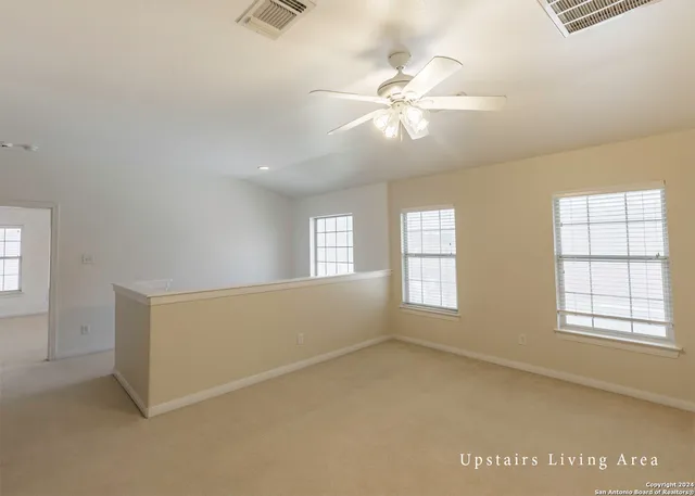 an empty room with windows and fan