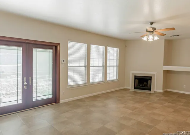 a view of an empty room with chandelier fan and fire place