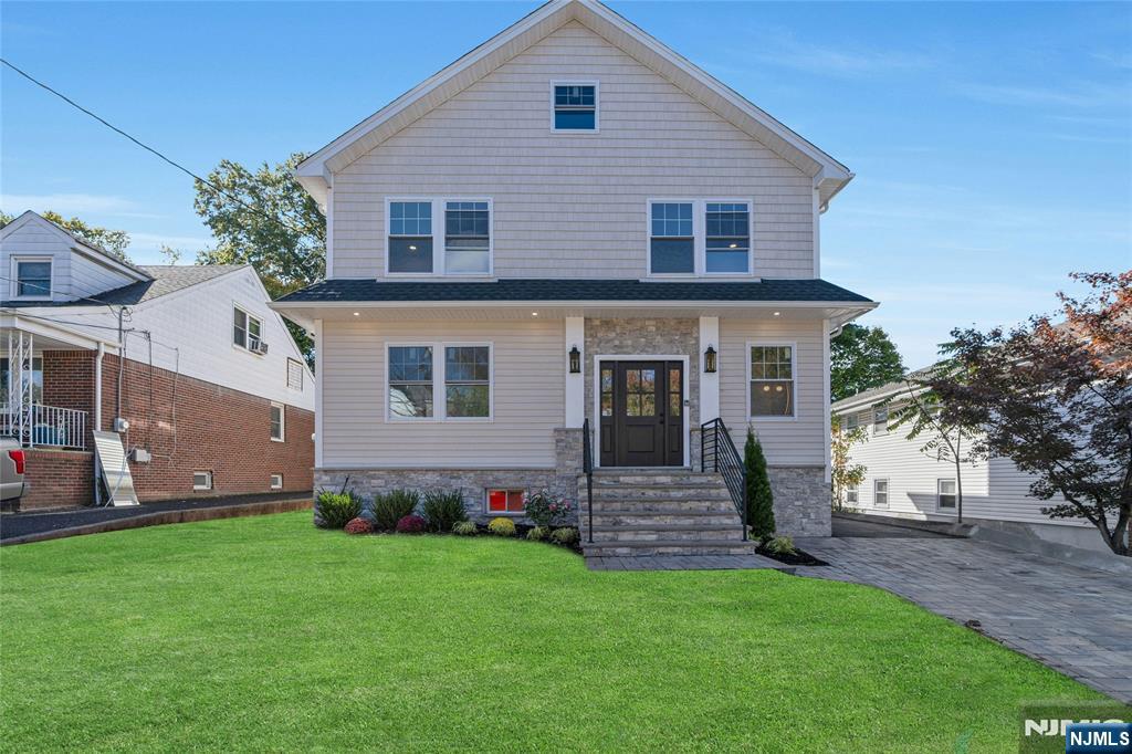 a view of a house with a yard potted plants and a large tree