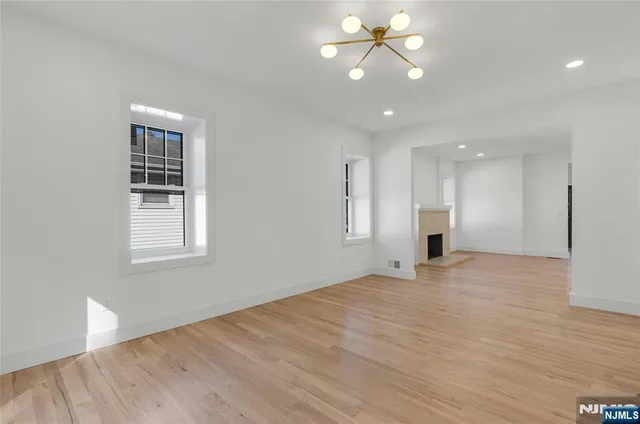 a view of an empty room with window and wooden floor