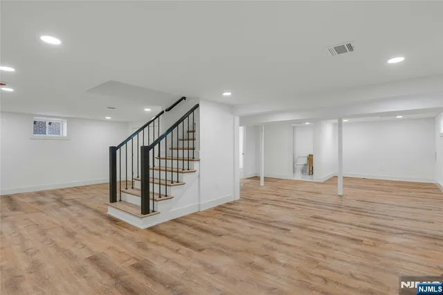 a view of an empty room with wooden floor and stairs