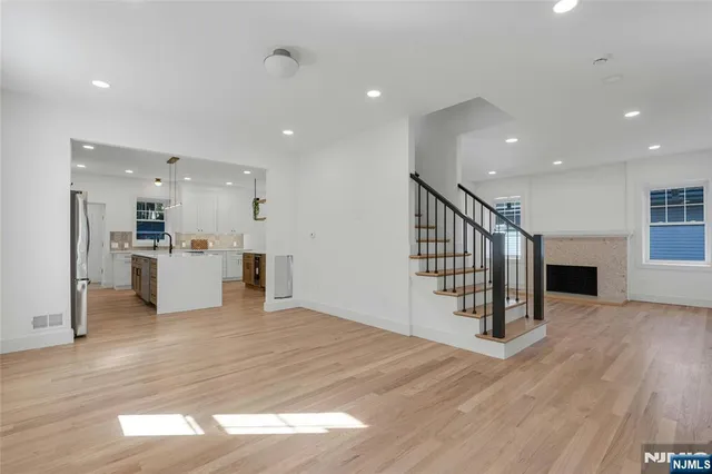 a view of an empty room with wooden floor and a kitchen