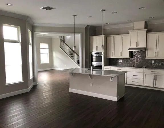 a kitchen with stainless steel appliances granite countertop a stove a sink a refrigerator and white cabinets with wooden floor