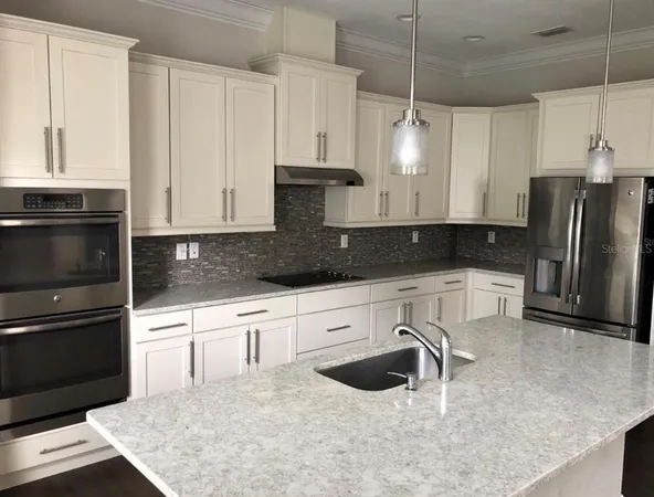 a kitchen with granite countertop white cabinets white stainless steel appliances and granite counter tops