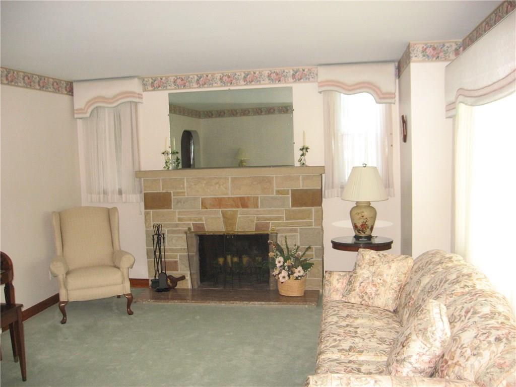 Living room with wood burning fireplace and hardwood flooring under the carpet.