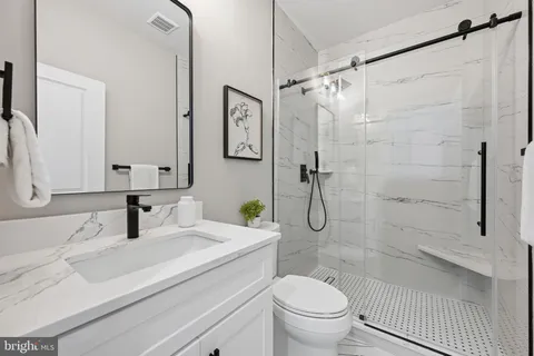 a bathroom with a shower sink vanity mirror and toilet