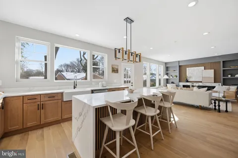 a view of a dining room and livingroom with furniture wooden floor a rug a painting and a chandelier
