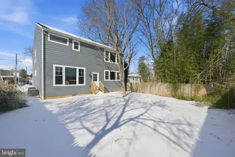 a backyard of a house with large trees and wooden fence