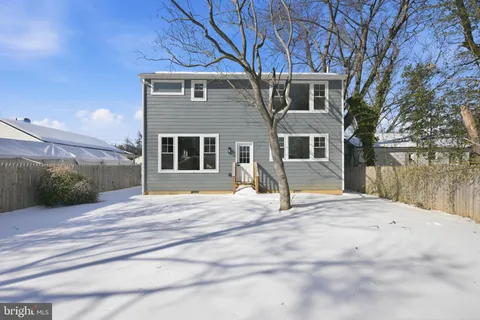 a backyard of a house with large trees and wooden fence