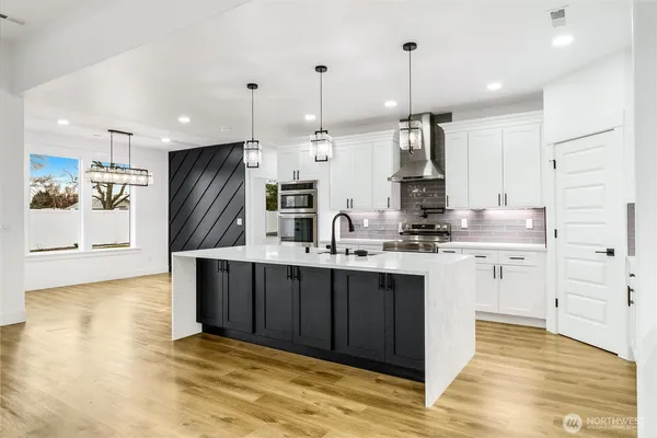 a kitchen with kitchen island granite countertop a sink cabinets and stainless steel appliances