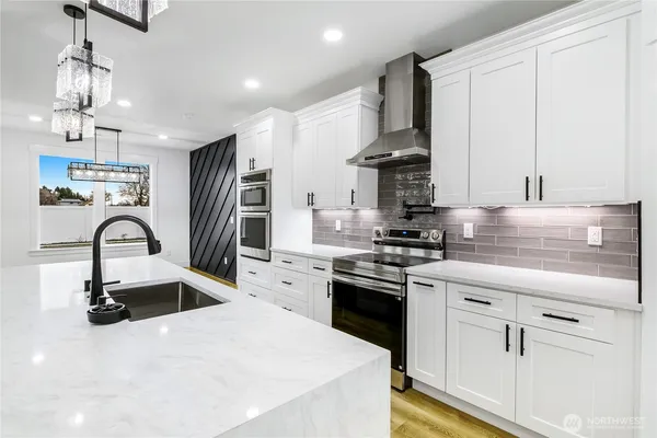 a kitchen with kitchen island granite countertop a sink stainless steel appliances and white cabinets