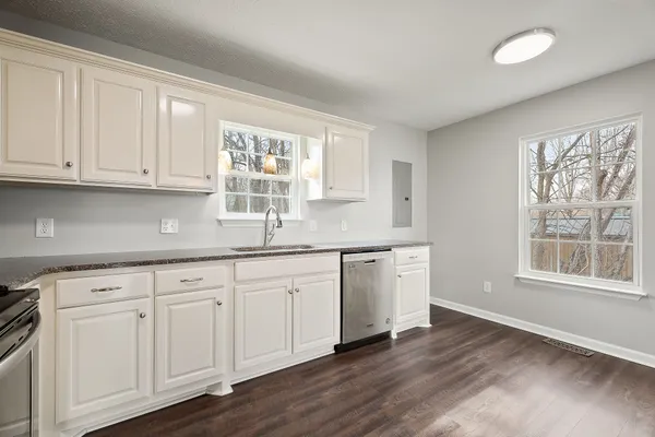 a kitchen with granite countertop white cabinets and a sink